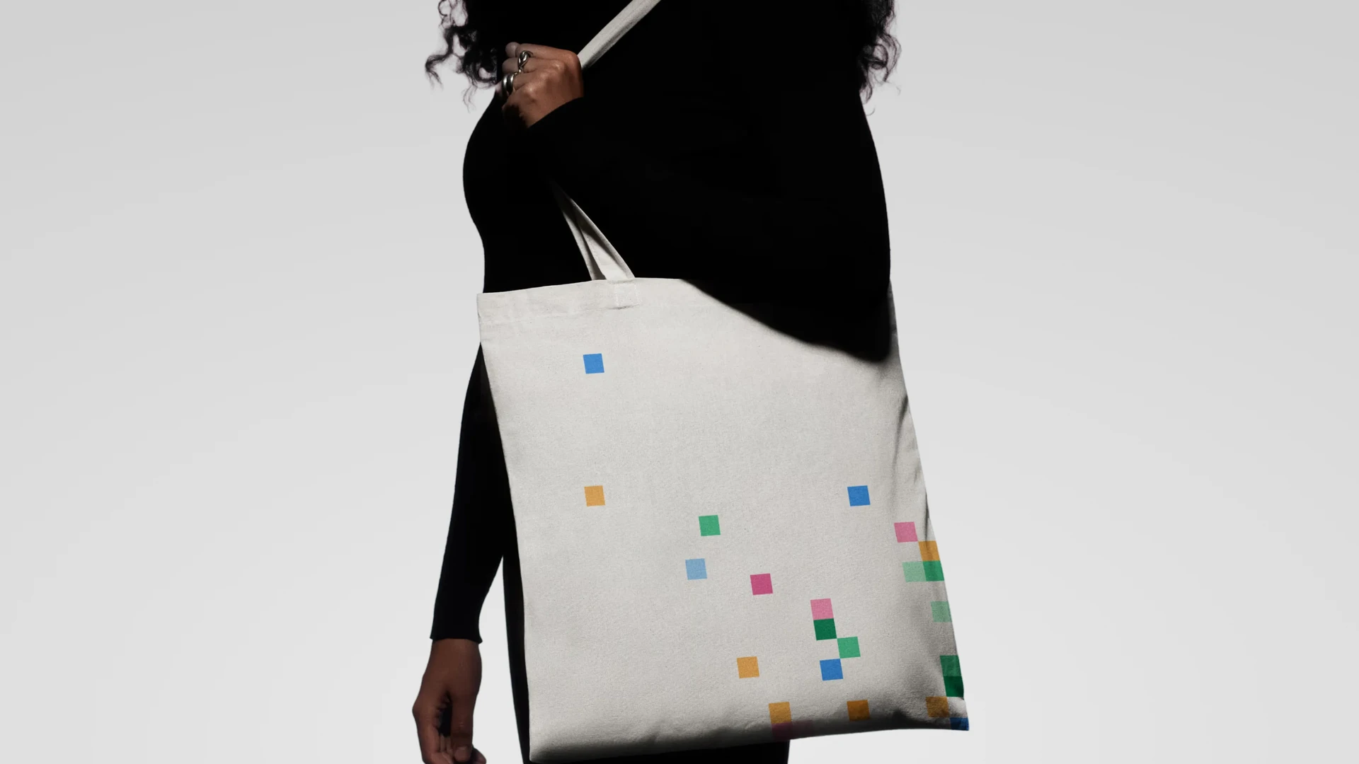 A white tote bag with colorful squares against a light gray background